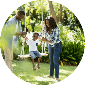 Two parents playing with their child on a swing