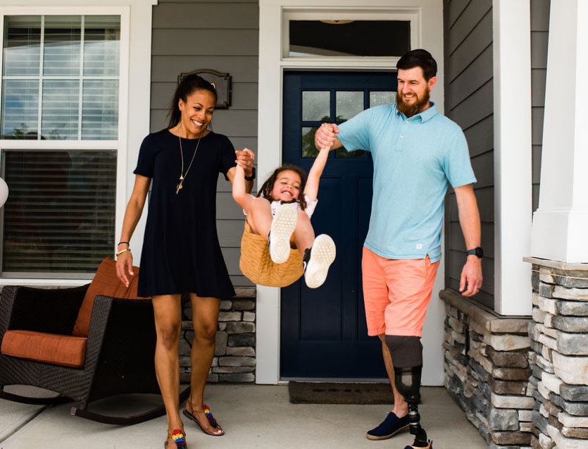 A family of 3 outside a house